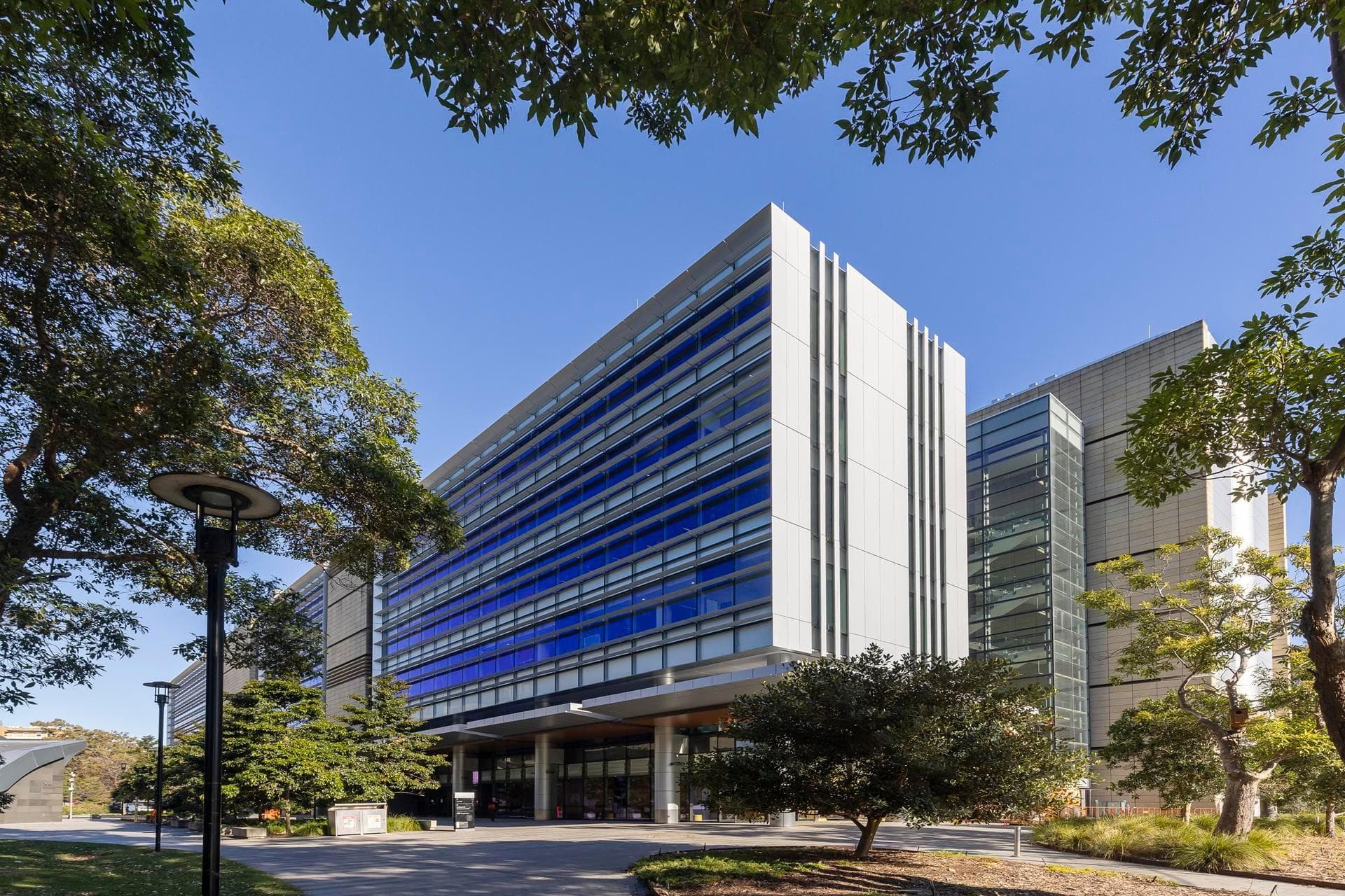 Wide architectural view of the Charles Perkins Centre featuring Alpolic NC silver and beige cladding with strong vertical lines.