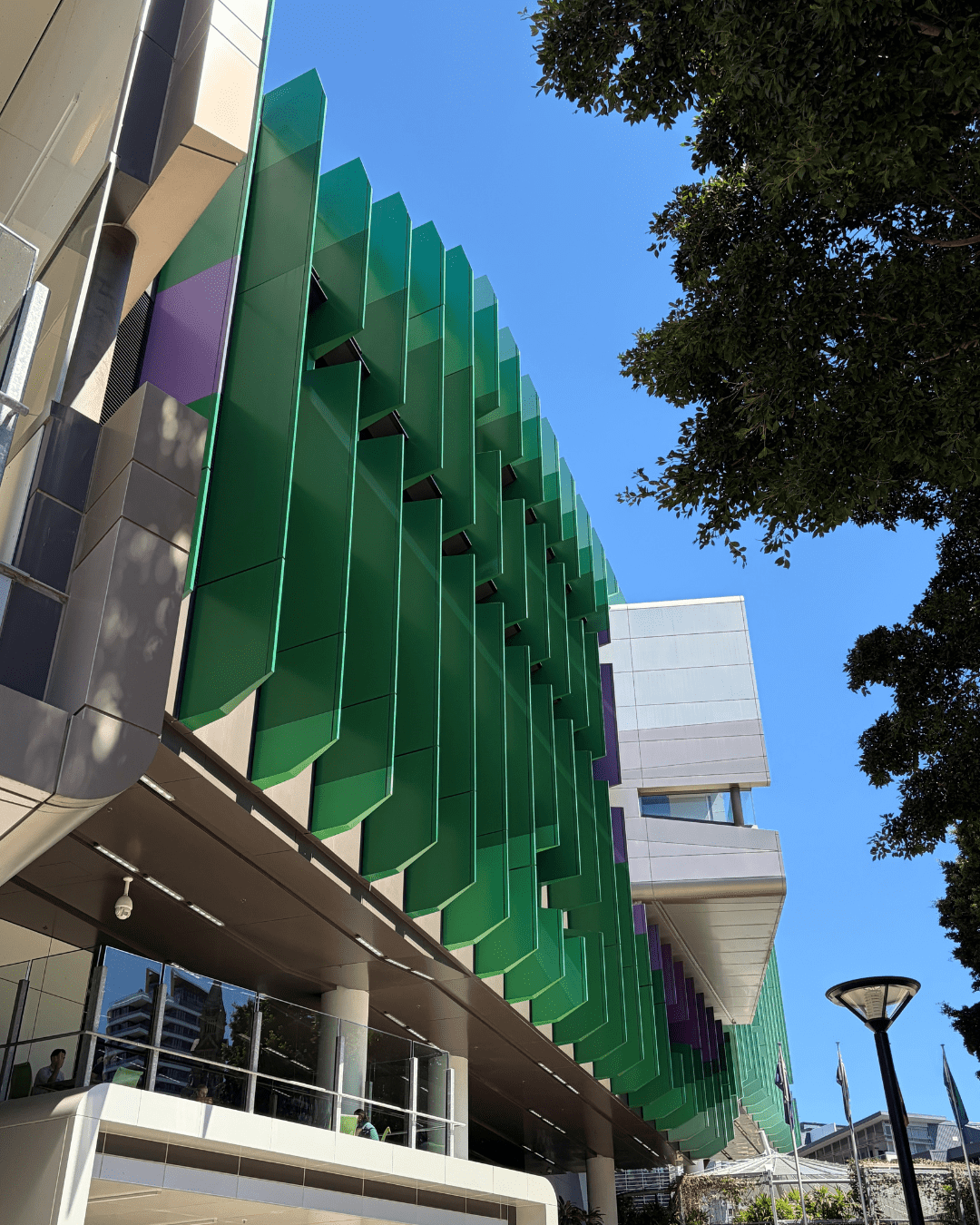 Alt: Queensland Children’s Hospital façade with vertical ALPOLIC™/fr green fins and coloured panels against blue sky