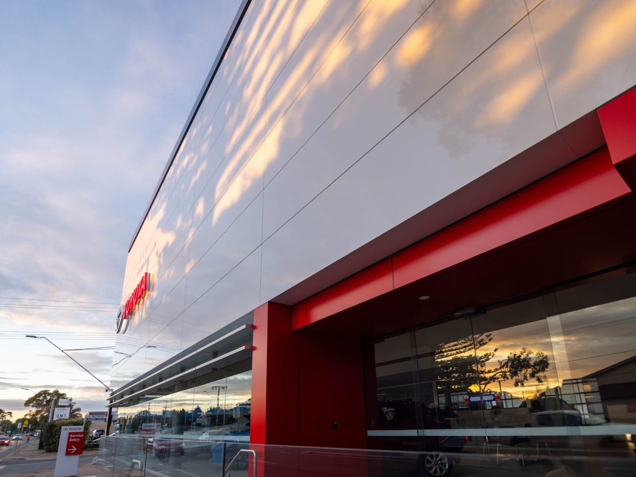 Close-up of Toyota dealership façade with glossy ALPOLIC™ architectural cladding and red entry feature